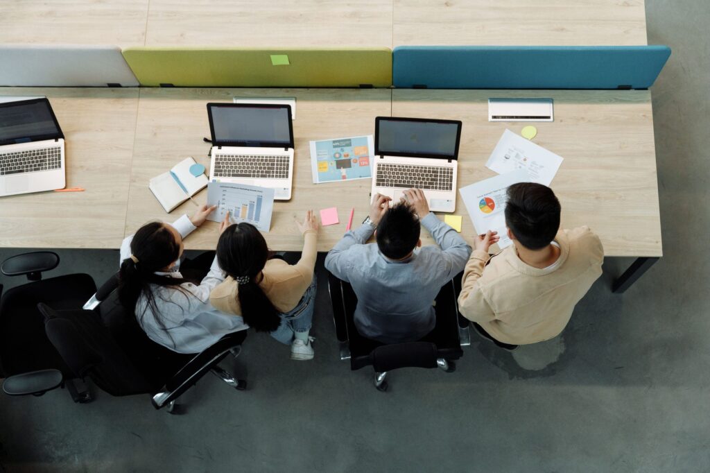 A small team working around one shared desk, seen from above
