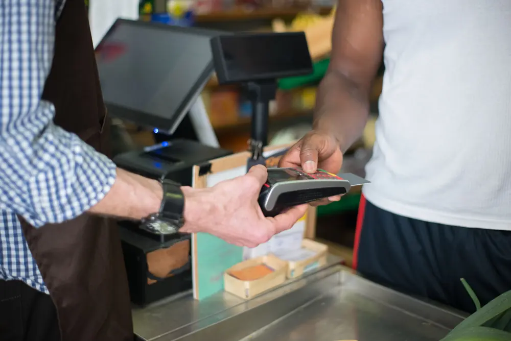 A customer using a card payment terminal at a shop counter.