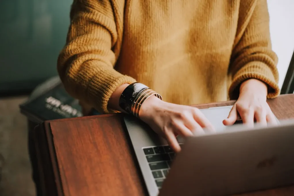 Hands typing on a laptop while working at a desk.