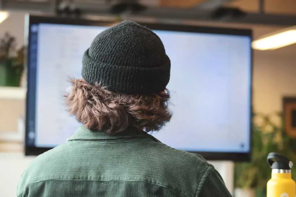 Rear view of a person checking a desktop computer at a desk.