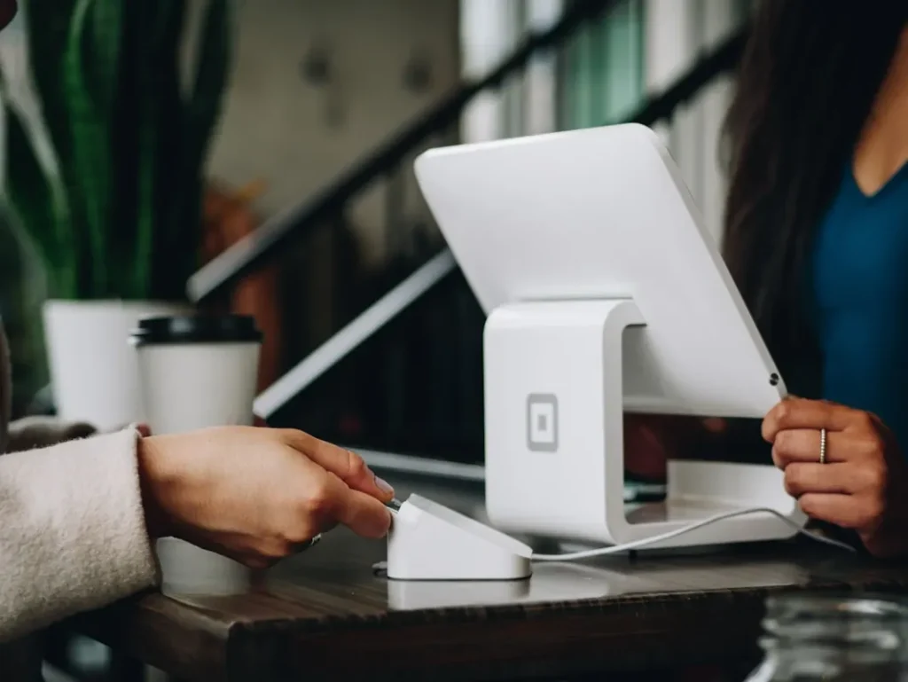 Hands using a payment terminal at a counter, illustrating a business payment.