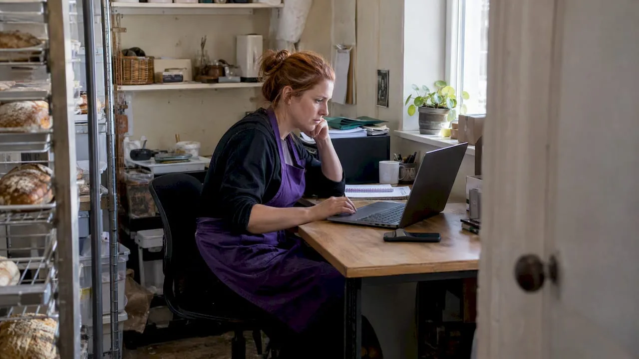Bakery owner checking email setup on laptop